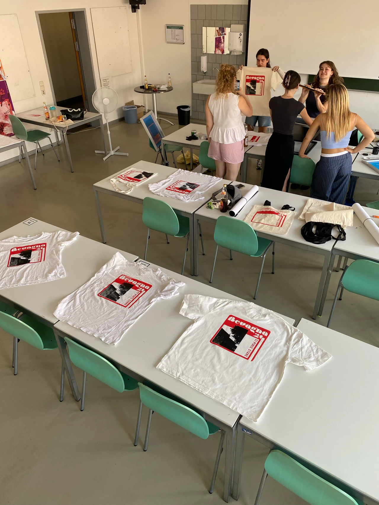 Mehrere bedruckte T-Shirts liegen im Workshopraum auf Tischen ausgelegt
